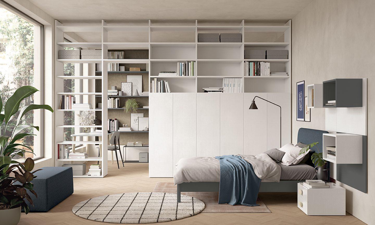 Cameretta con parete libreria bianca a tutta altezza che suddivide lo spazio tra zona letto e zona studio, letto singolo con testiera imbottita blu e comodini sospesi, collezione Golf Young's space