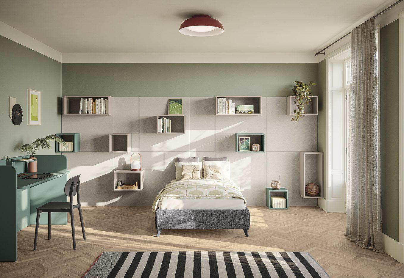 Parete boiserie imbottita grigia con composizione di cubi contenitori sospesi verde salvia, tortora e crema per esporre ed archiviare, letto singolo grigio e scrittoio verde salvia, collezione Golf Young's space