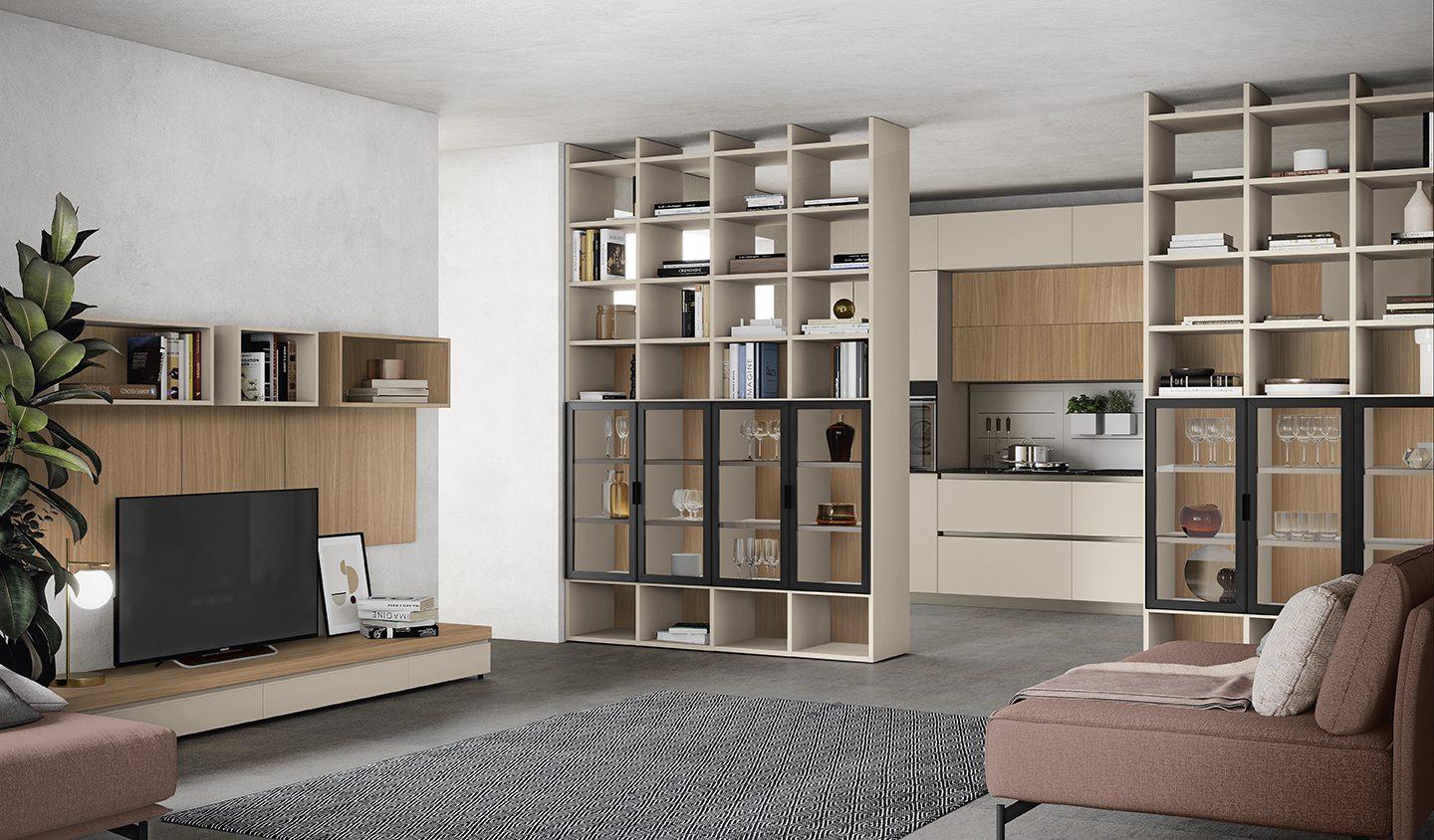 Soggiorno open space con cucina, libreria a scomparsa con vetrinette illuminate e divano rosa antico