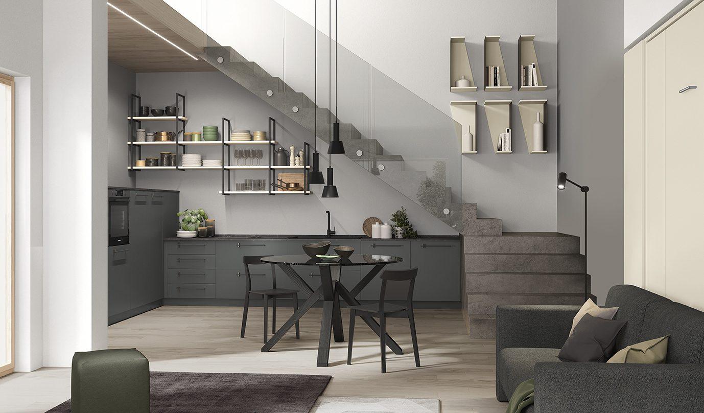 Zona living sottoscala con cucina grigio antracite, tavolo rotondo in vetro fumè e libreria a mensole sospese
