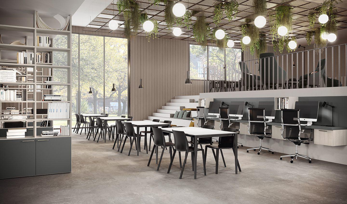 Sala studio con tavoli e sedie in fila, postazioni con monitor e scaffalature libreria in legno chiaro