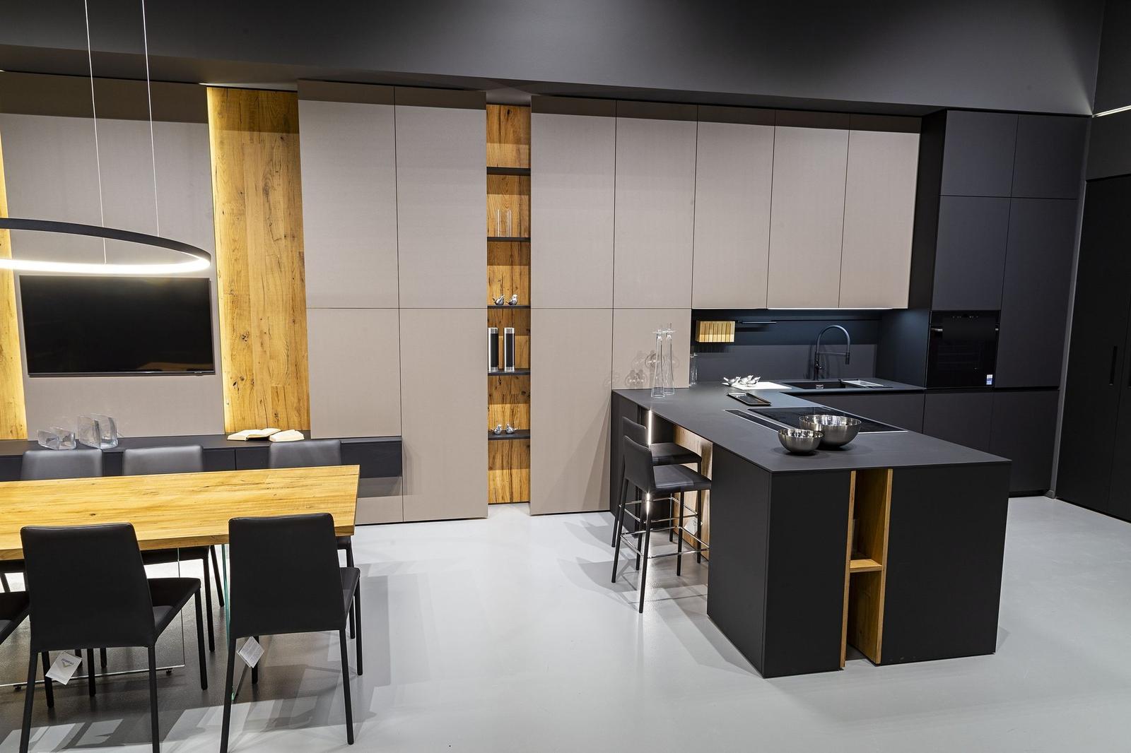 Cucina open space con isola nera, dettagli in legno e zona pranzo
