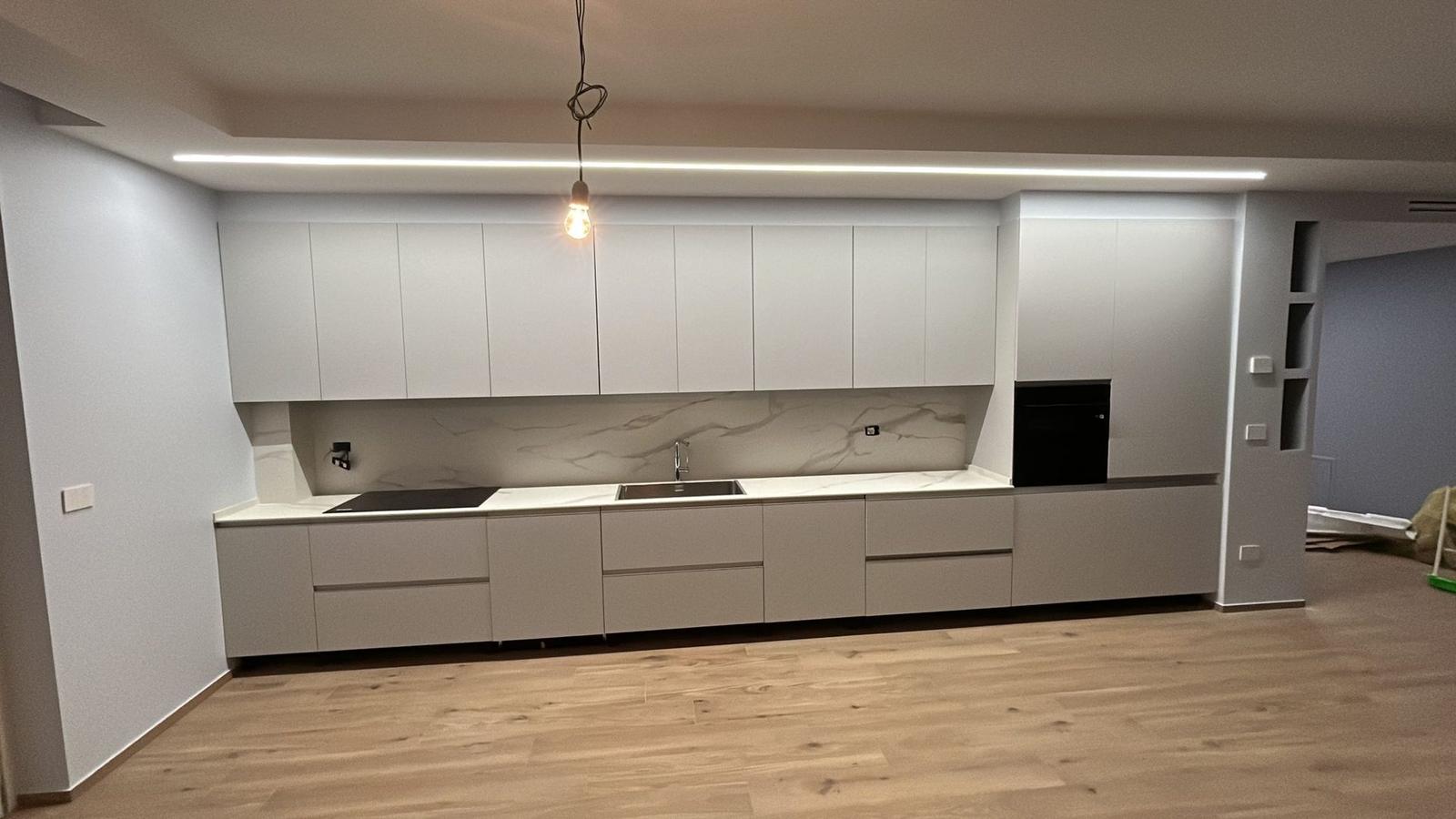 Cucina lineare bianca con illuminazione a soffitto e penisola