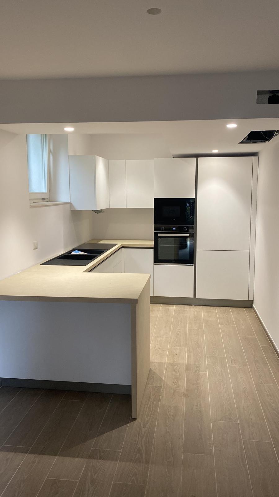 Cucina bianca ad angolo con colonna forno e microonde a incasso