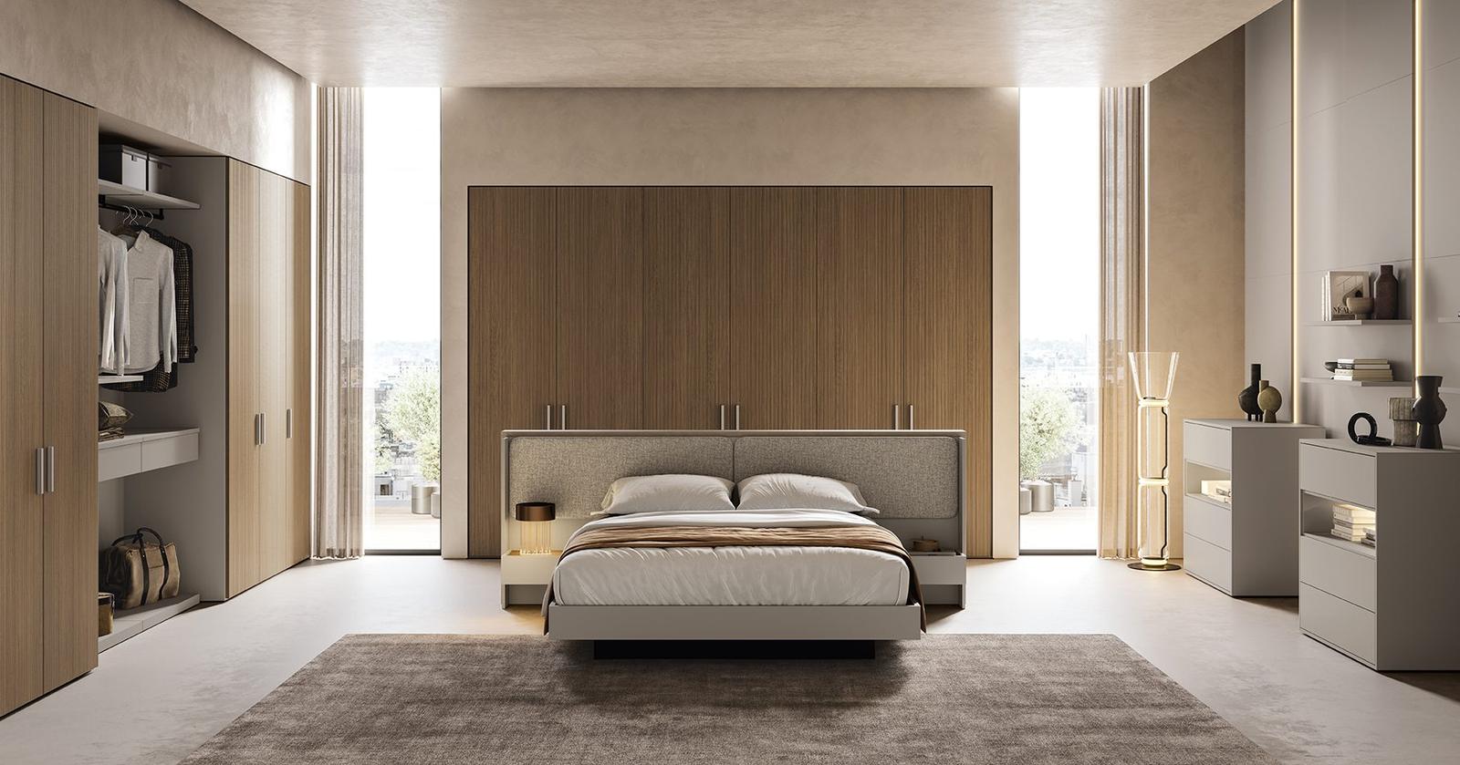 Camera da letto ampia con boiserie in legno di rovere a tutta parete, testata imbottita grigio tortora, comodini sospesi con luce led e cabina armadio a vista con ante scorrevoli in vetro