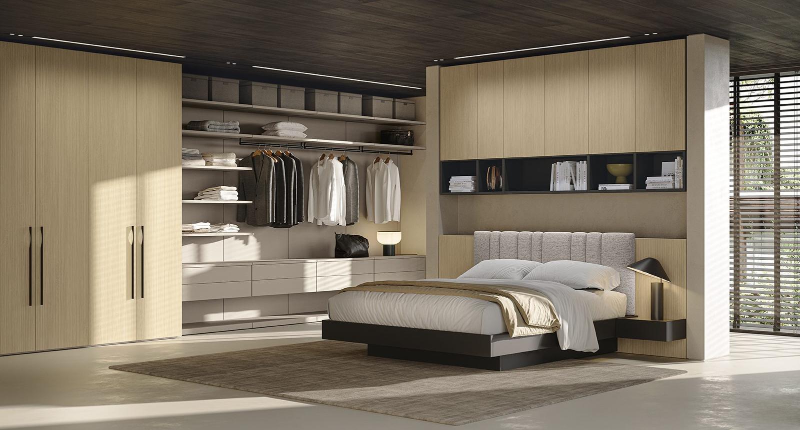 Camera da letto con boiserie in legno chiaro a tutta parete, nicchie a giorno con libreria integrata, testata imbottita grigia e cabina armadio con ante scorrevoli in legno