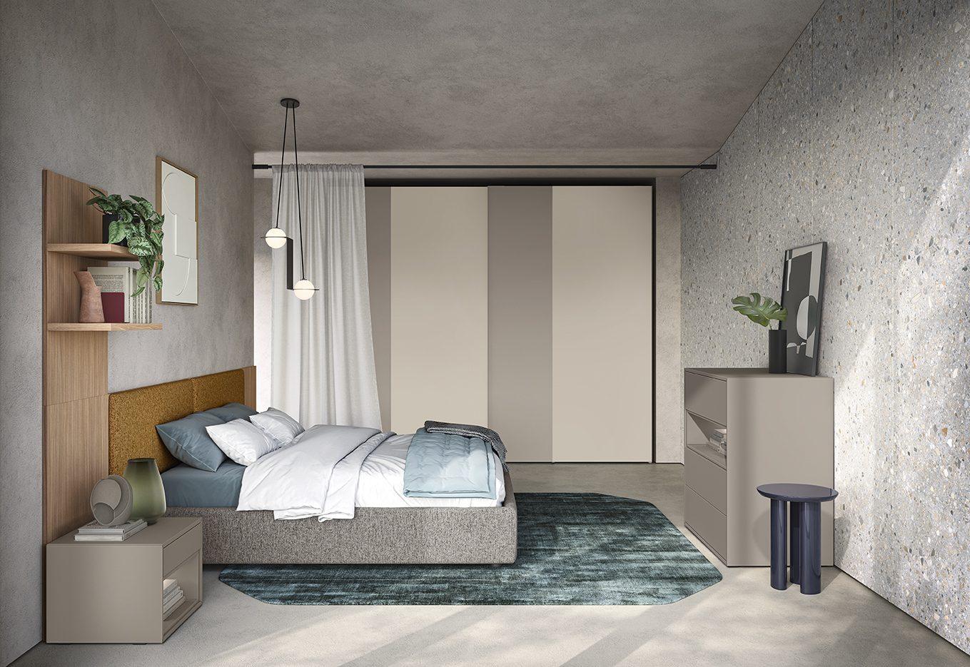Camera da letto con testata imbottita in tessuto boucle color senape, biancheria azzurro polvere, armadio con ante scorrevoli bicolore tortora e grigio e comodino con libreria a giorno in legno