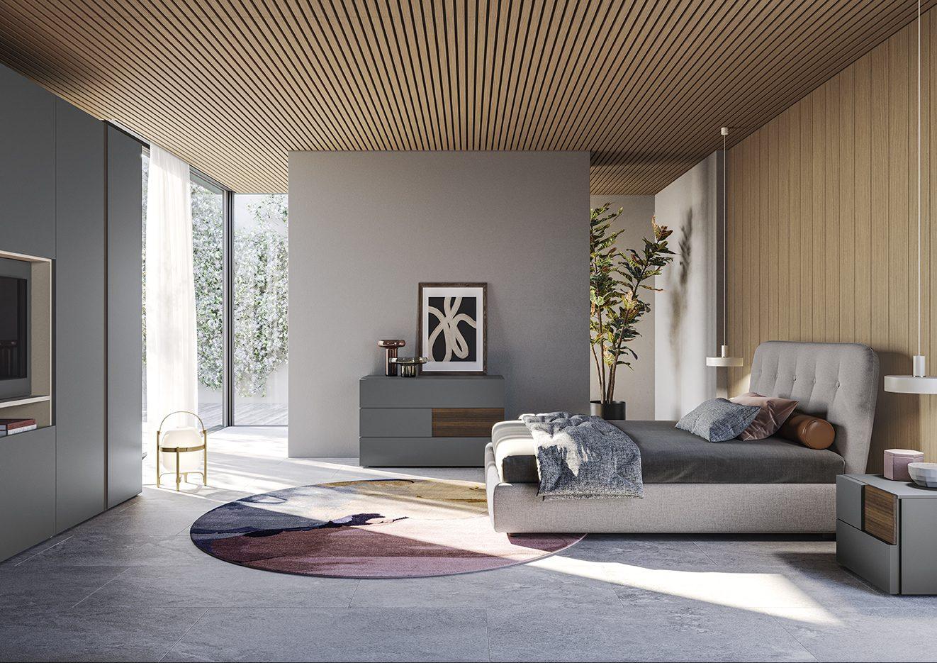 Camera da letto con testata imbottita capitonné color tortora, comò laccato grigio con inserti in legno di noce, tappeto rotondo bicolore e parete boiserie in doghe di legno chiaro