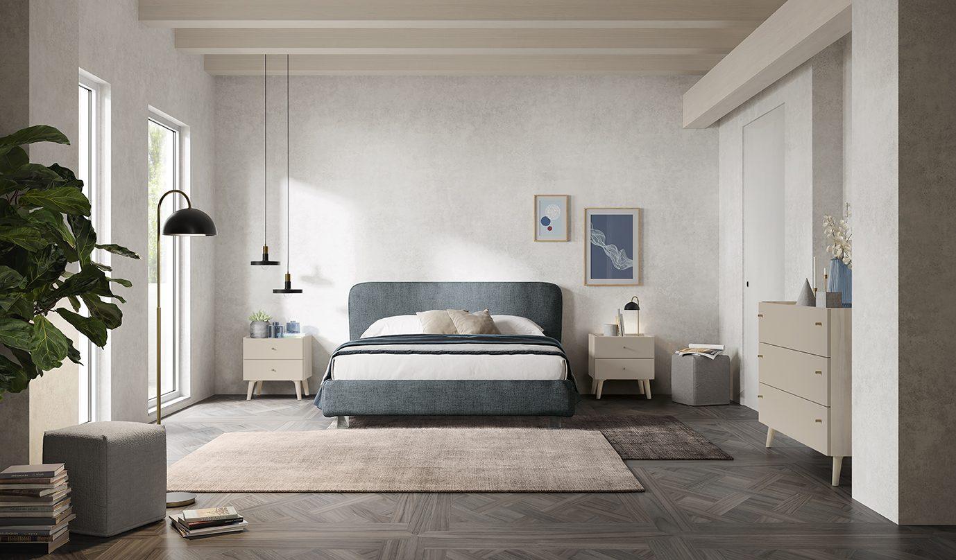 Camera da letto con testata imbottita azzurro polvere su gambe in legno, comodini abbinati e cassettiera laccata avorio, pavimento in parquet a spina
