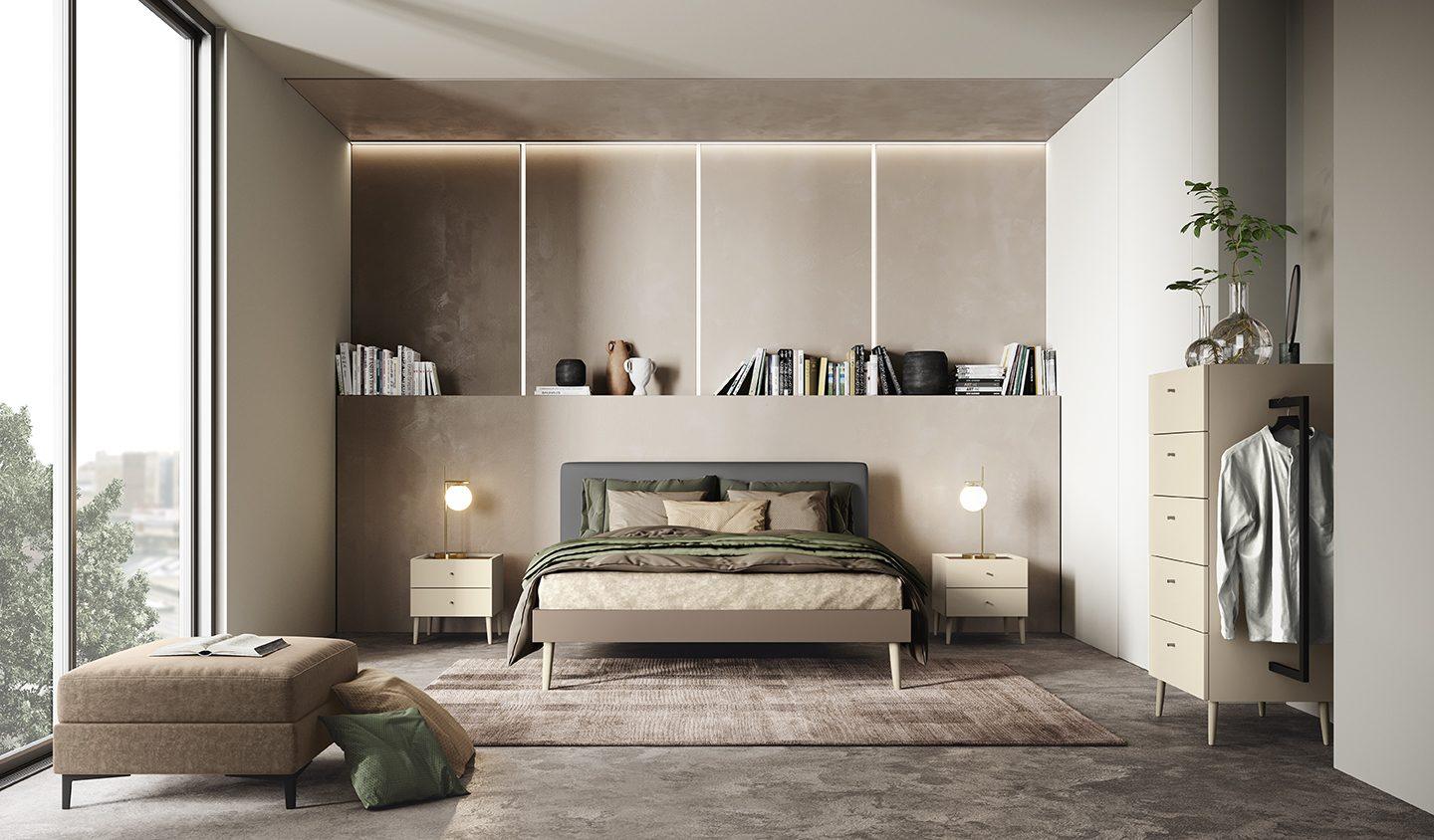 Camera da letto con boiserie a tutta parete con libreria a giorno illuminata, testata imbottita grigio antracite, comodini su gambe laccati avorio e cassettiera con appendiabiti a vista
